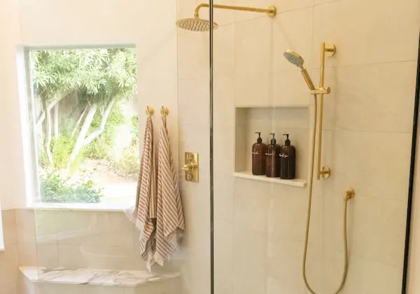 Dusch med varmt beige kakel och detaljer i mässing.